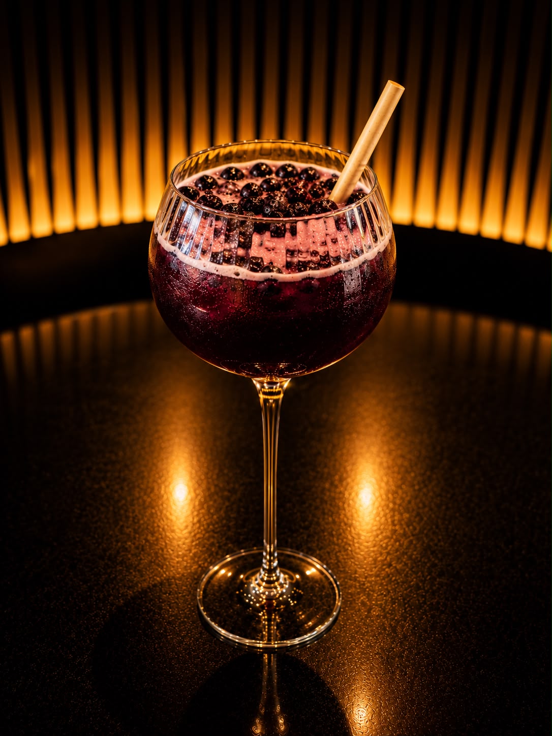 Le Blue Velvet, spritz violet profond couvert de myrtilles fraîches, dans un verre à pied ciselé