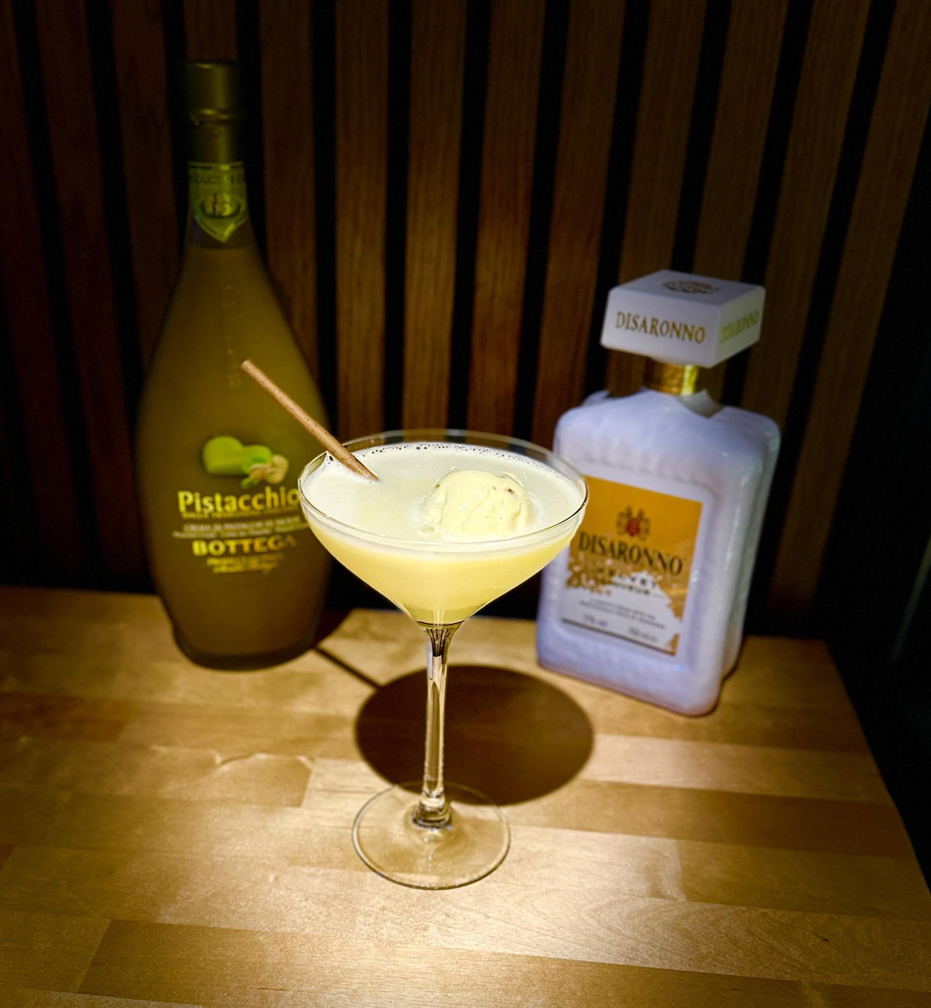 Un cocktail crémeux à la pistache, surmonté d'une boule de glace et d'un bâton de cannelle