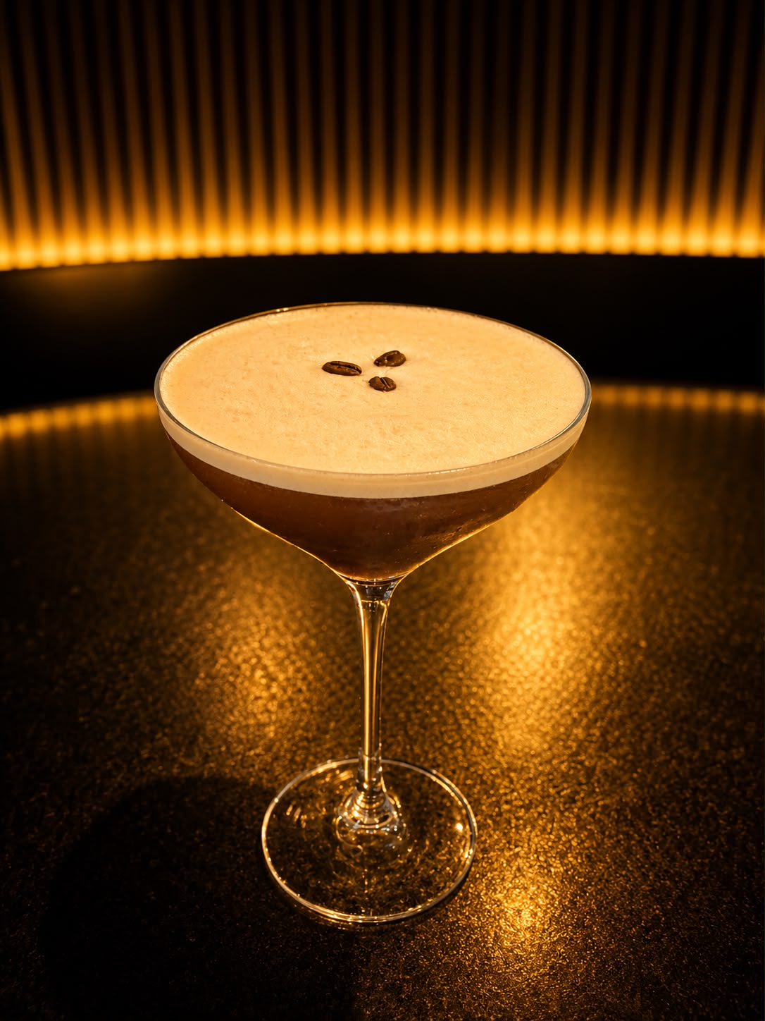 Un Espresso Martini à la mousse dorée, surmonté de trois grains de café